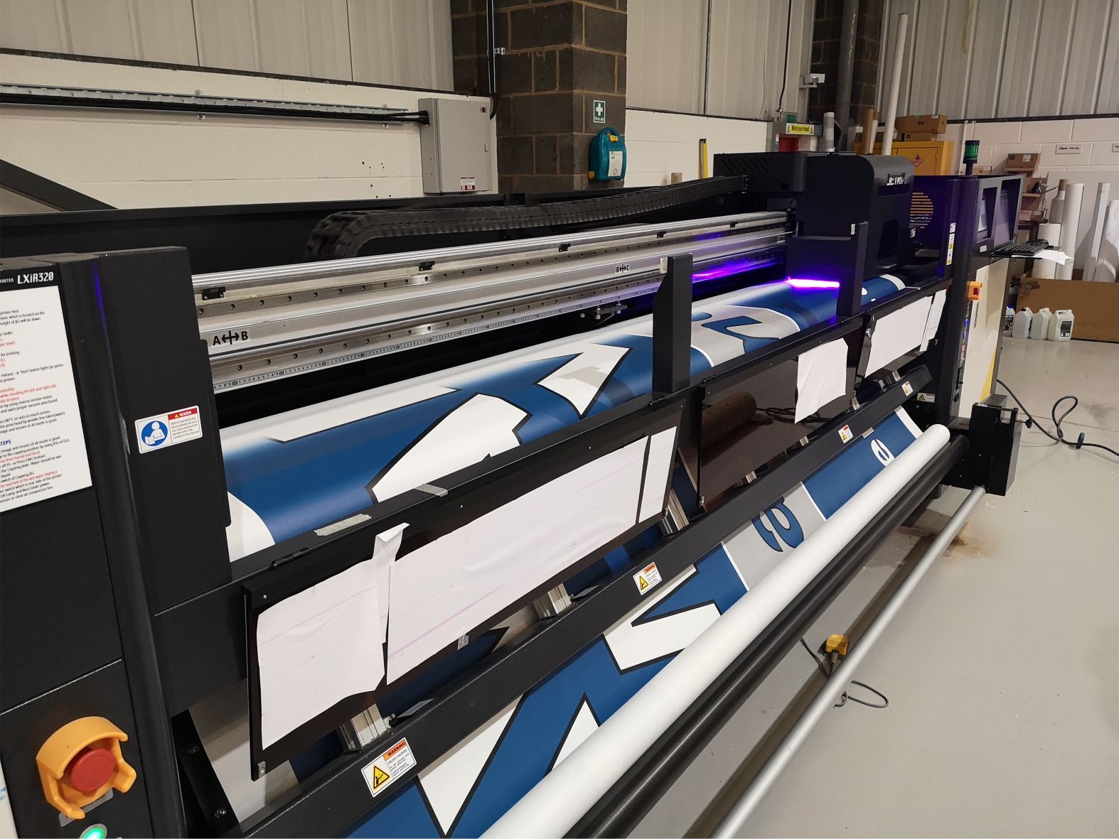 A printing machine displaying a high-quality sign printing process. Alt text: Printing machine producing high-quality printed signage during the production process.